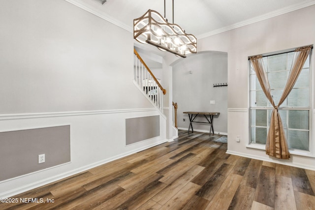 foyer entrance with ornamental molding, dark hardwood / wood-style floors, and a notable chandelier