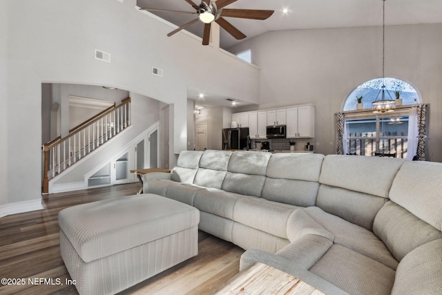 living room featuring ceiling fan with notable chandelier, wood-type flooring, and high vaulted ceiling