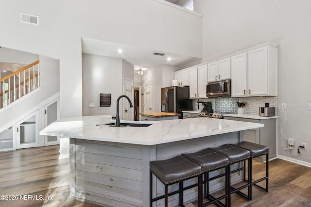 kitchen with a center island with sink, sink, a towering ceiling, and stainless steel appliances