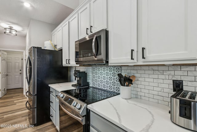 kitchen featuring white cabinets, light stone counters, stainless steel appliances, and tasteful backsplash