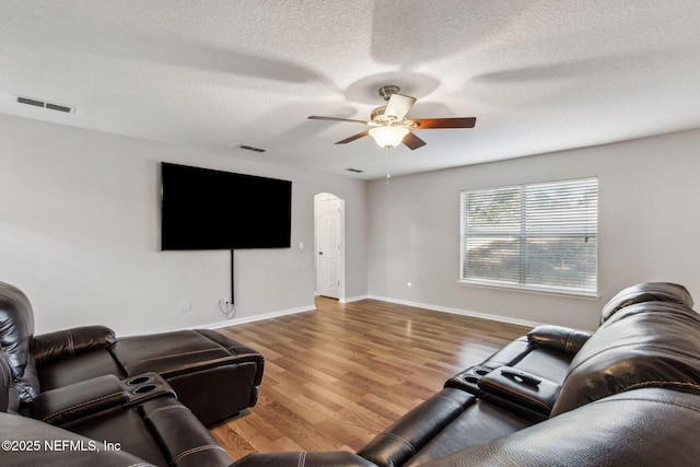 living room featuring ceiling fan, hardwood / wood-style floors, and a textured ceiling