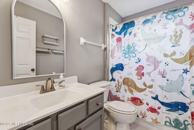 bathroom featuring curtained shower, vanity, and toilet