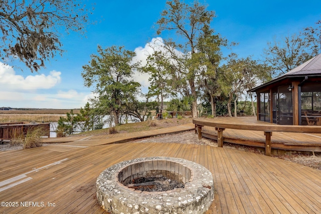 wooden deck with an outdoor fire pit and a sunroom