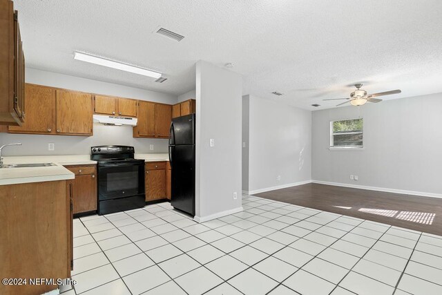 kitchen with ceiling fan, sink, a textured ceiling, light tile patterned floors, and black appliances