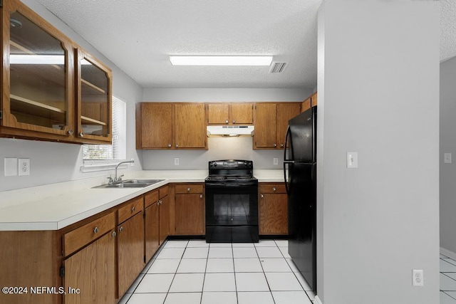 kitchen with black appliances, light tile patterned flooring, sink, and a textured ceiling