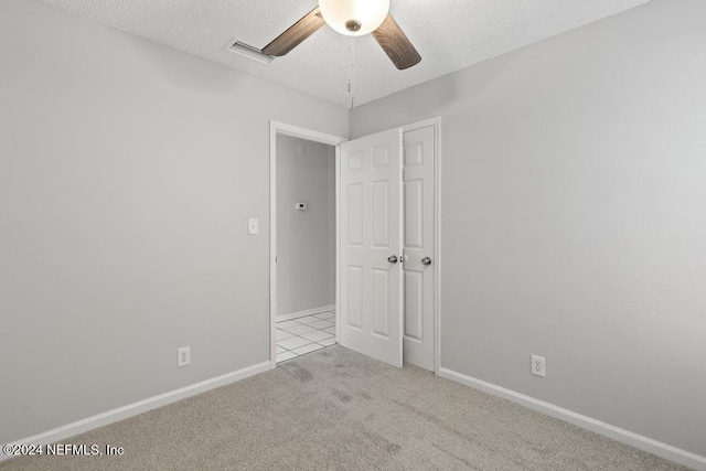 carpeted spare room with ceiling fan and a textured ceiling