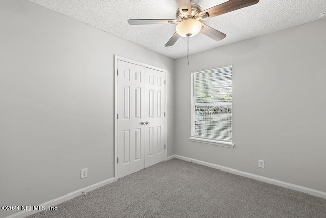 unfurnished bedroom featuring carpet flooring, ceiling fan, a textured ceiling, and a closet