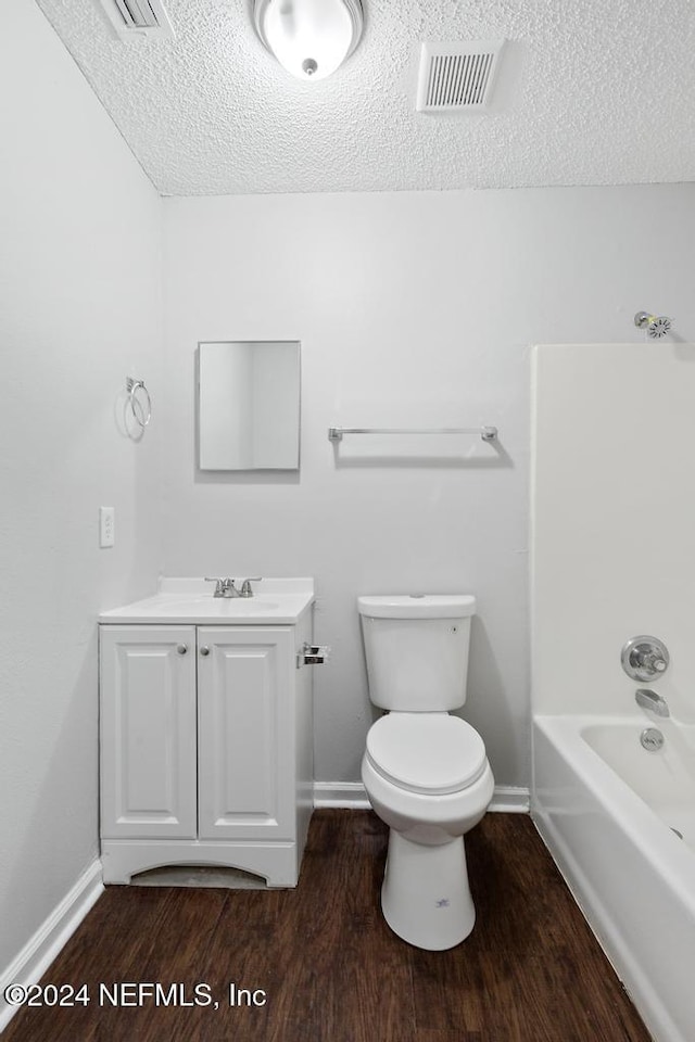 full bathroom with wood-type flooring, vanity, a textured ceiling, and toilet