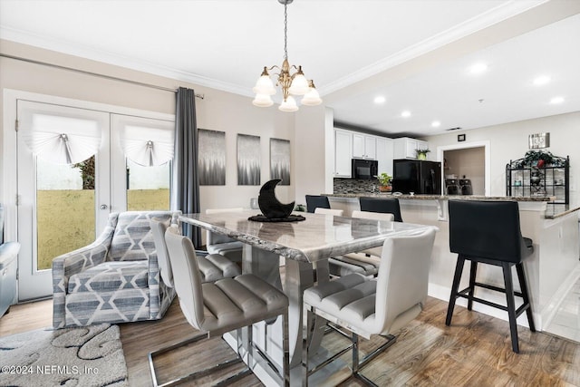 dining area with hardwood / wood-style floors, a chandelier, and ornamental molding