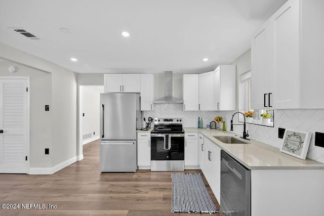 kitchen with white cabinets, wall chimney exhaust hood, sink, and stainless steel appliances