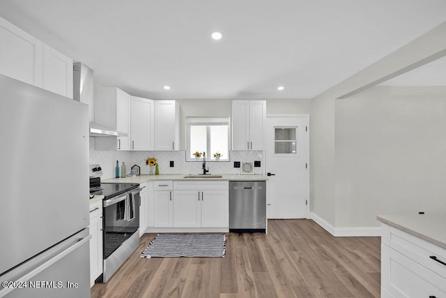 kitchen featuring white cabinetry, sink, wall chimney exhaust hood, and appliances with stainless steel finishes