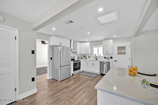 kitchen featuring white cabinets, wall chimney exhaust hood, light stone countertops, tasteful backsplash, and stainless steel appliances