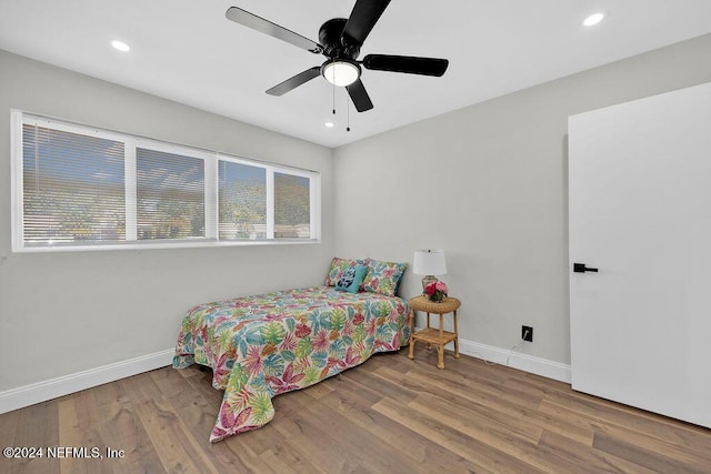 bedroom featuring hardwood / wood-style flooring, ceiling fan, and multiple windows