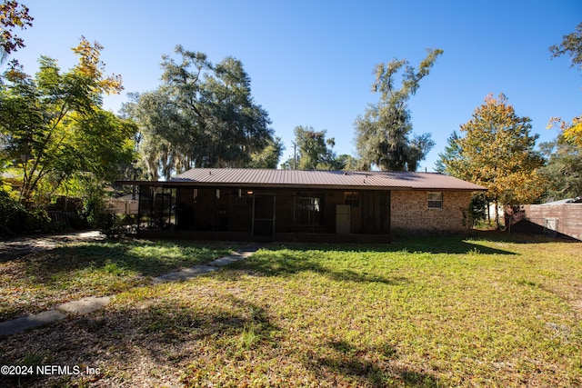 back of house with a lawn and a sunroom