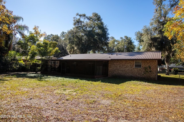 rear view of house featuring a sunroom and a lawn