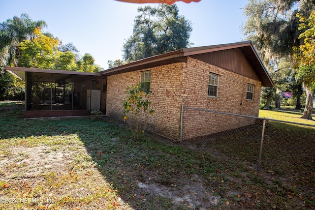 view of side of property featuring a lawn and a sunroom