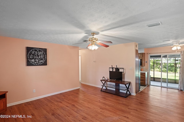 unfurnished living room with a textured ceiling, light wood-type flooring, and ceiling fan