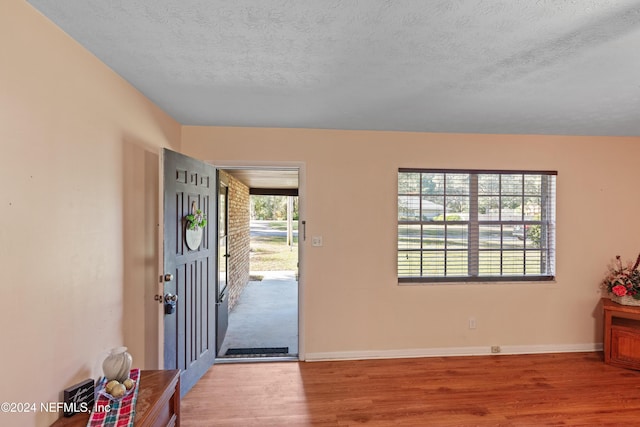 entryway with a textured ceiling and light hardwood / wood-style flooring