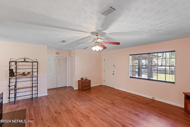 unfurnished room with hardwood / wood-style flooring, ceiling fan, and a textured ceiling