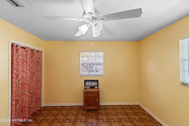 spare room featuring a textured ceiling, dark parquet floors, and ceiling fan