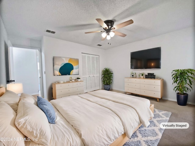 bedroom with ceiling fan, a textured ceiling, light carpet, and a closet