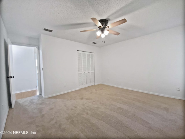 carpeted spare room with ceiling fan and a textured ceiling