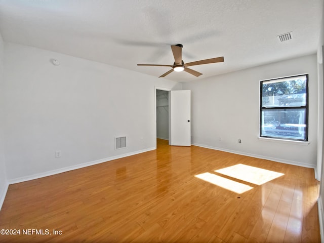 empty room featuring ceiling fan, light hardwood / wood-style flooring, and a textured ceiling