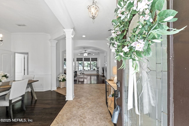 tiled foyer with decorative columns, crown molding, and ceiling fan with notable chandelier