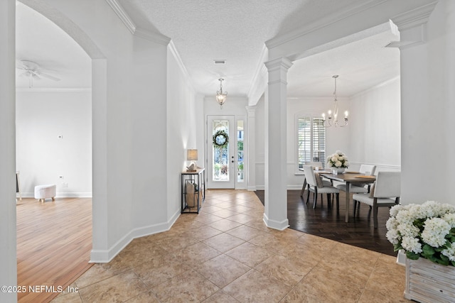 foyer with a textured ceiling, crown molding, light tile patterned floors, and ceiling fan with notable chandelier