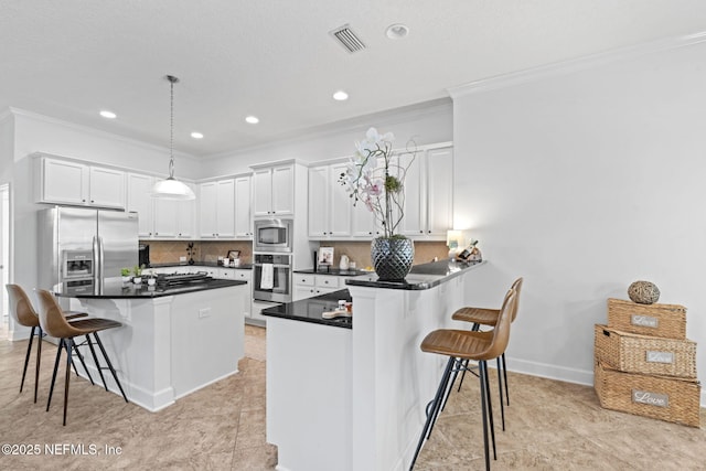 kitchen with tasteful backsplash, pendant lighting, a kitchen bar, white cabinets, and appliances with stainless steel finishes