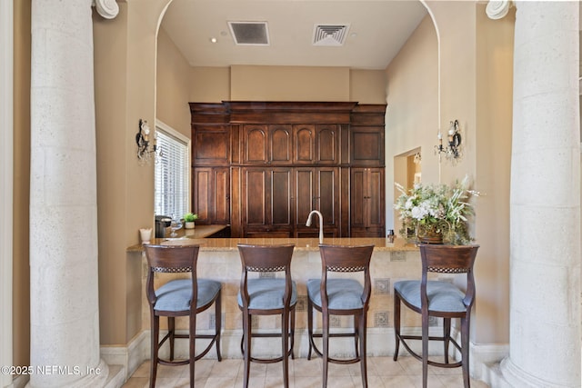 bar featuring dark brown cabinets and light tile patterned floors