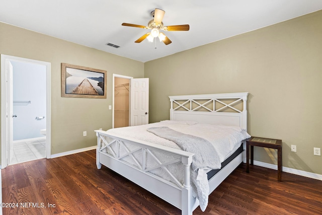 bedroom featuring ceiling fan, a spacious closet, connected bathroom, dark hardwood / wood-style floors, and a closet