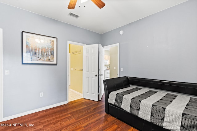 bedroom with ceiling fan, dark hardwood / wood-style flooring, a spacious closet, and washer / dryer