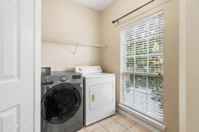 laundry room featuring washing machine and clothes dryer, light tile patterned floors, and a healthy amount of sunlight