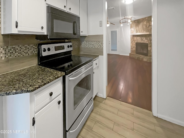 kitchen with white cabinetry, backsplash, a fireplace, and electric stove