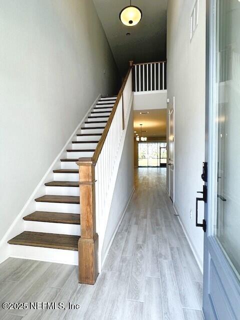 stairs featuring a towering ceiling, baseboards, visible vents, and wood finished floors