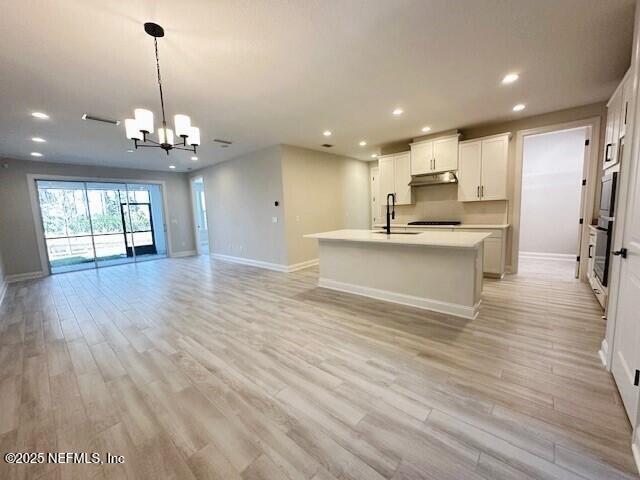 kitchen featuring an inviting chandelier, open floor plan, a sink, and oven