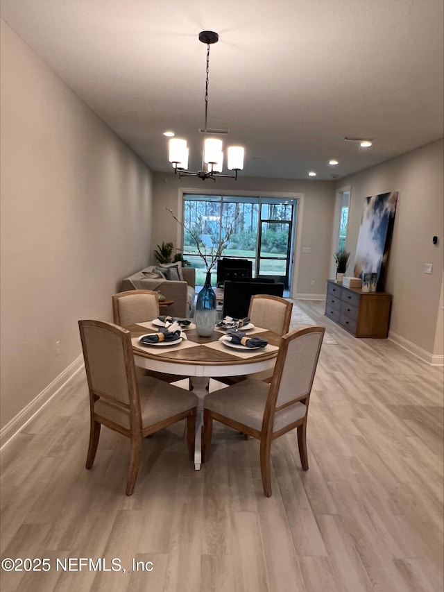 dining room featuring a chandelier, baseboards, and light wood finished floors