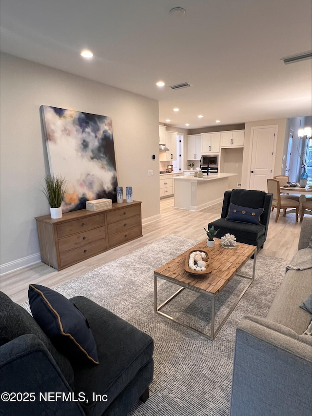 living area with baseboards, light wood finished floors, visible vents, and recessed lighting