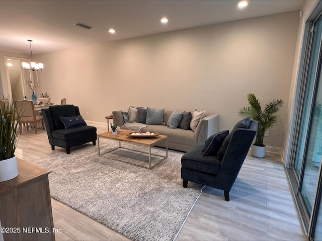 living area with light wood-type flooring, visible vents, recessed lighting, and an inviting chandelier