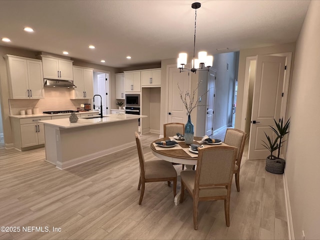 dining area featuring light wood-type flooring, baseboards, a notable chandelier, and recessed lighting