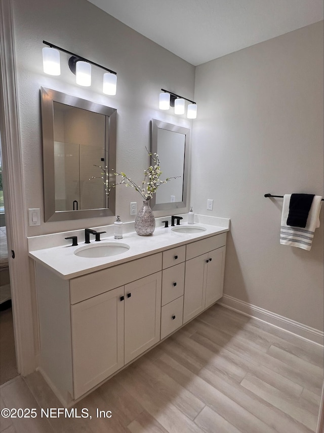 bathroom with double vanity, a sink, baseboards, and wood finished floors