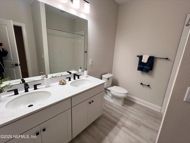 bathroom featuring a shower, a sink, toilet, and wood finished floors