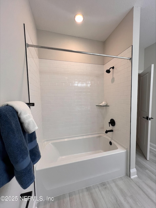 bathroom with wood finished floors and bathing tub / shower combination