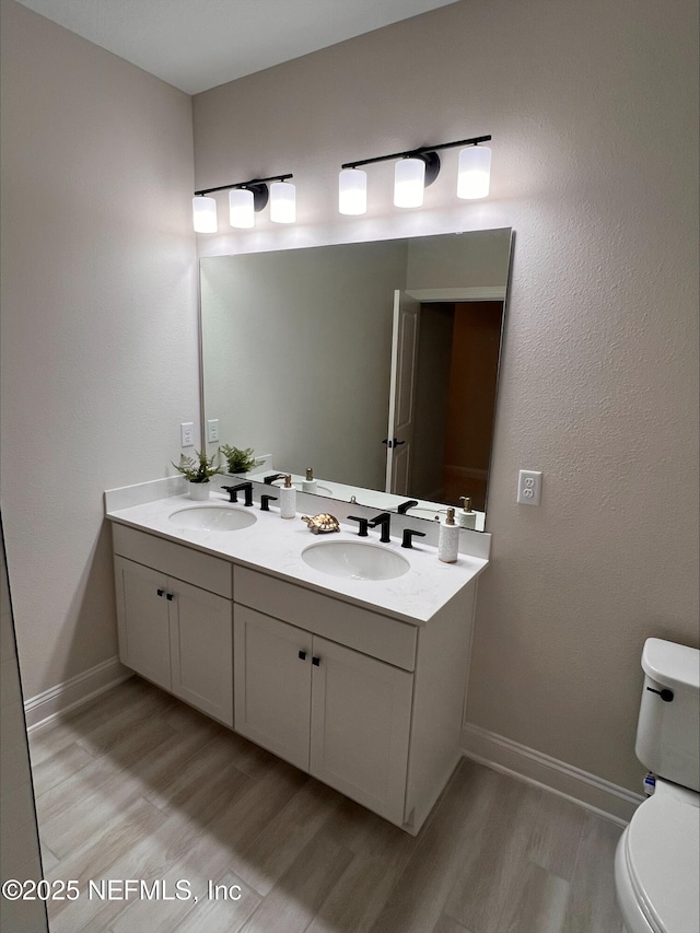 bathroom featuring toilet, a sink, and wood finished floors