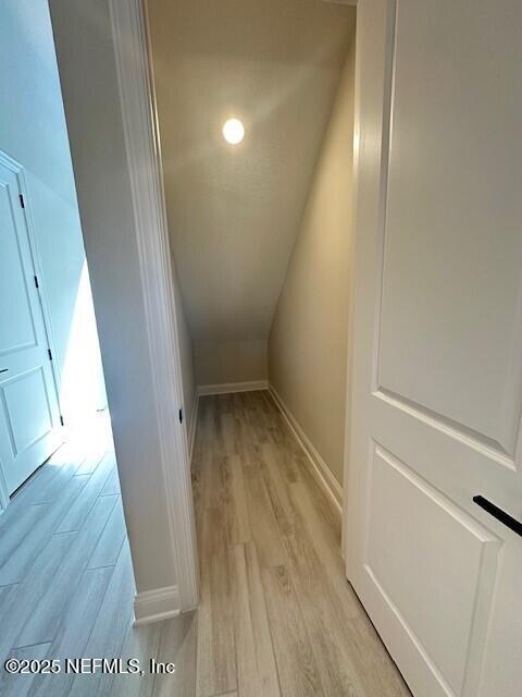 corridor featuring light wood finished floors and baseboards