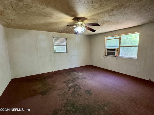 carpeted empty room with ceiling fan, a healthy amount of sunlight, a textured ceiling, and cooling unit