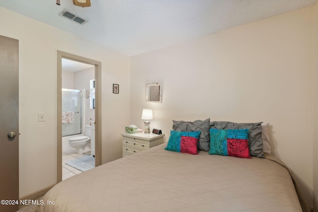 bedroom with connected bathroom, ceiling fan, light tile patterned floors, and a textured ceiling