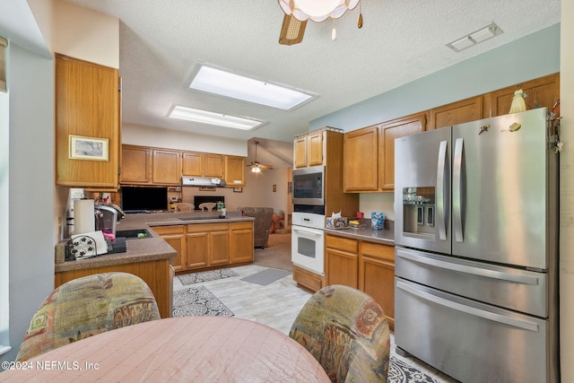 kitchen with kitchen peninsula, ceiling fan, stainless steel appliances, and a textured ceiling