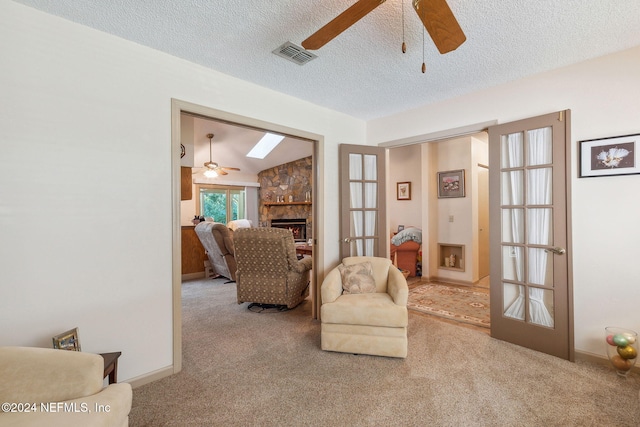 living area featuring ceiling fan, french doors, a textured ceiling, a fireplace, and carpet